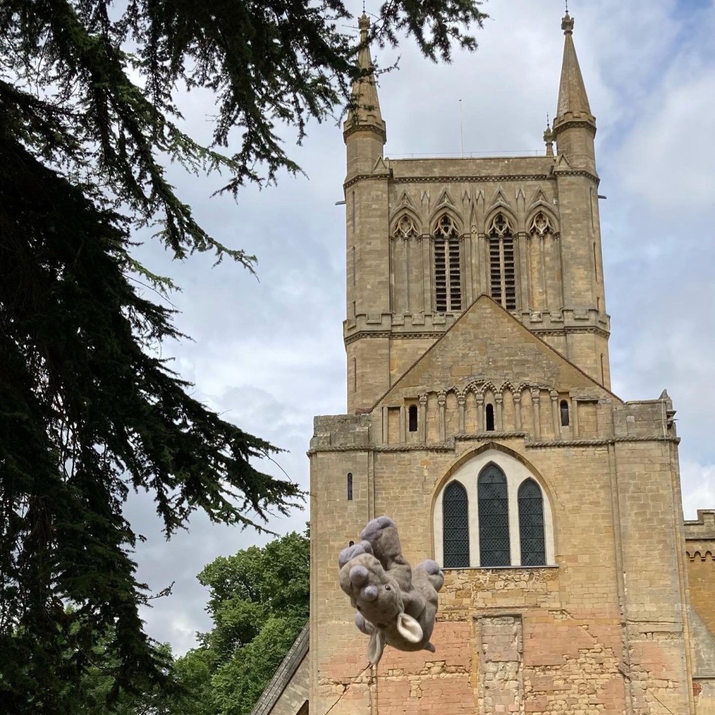 October on the calendar and Ronnie jumps for joy at pershore Abbey. He is coming down backwards and his eyes meet the camera.